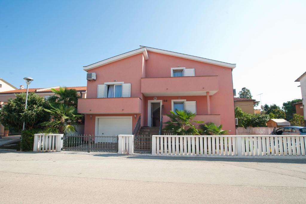 a pink house with a white fence in front of it at Apartments Maric with parking in Umag