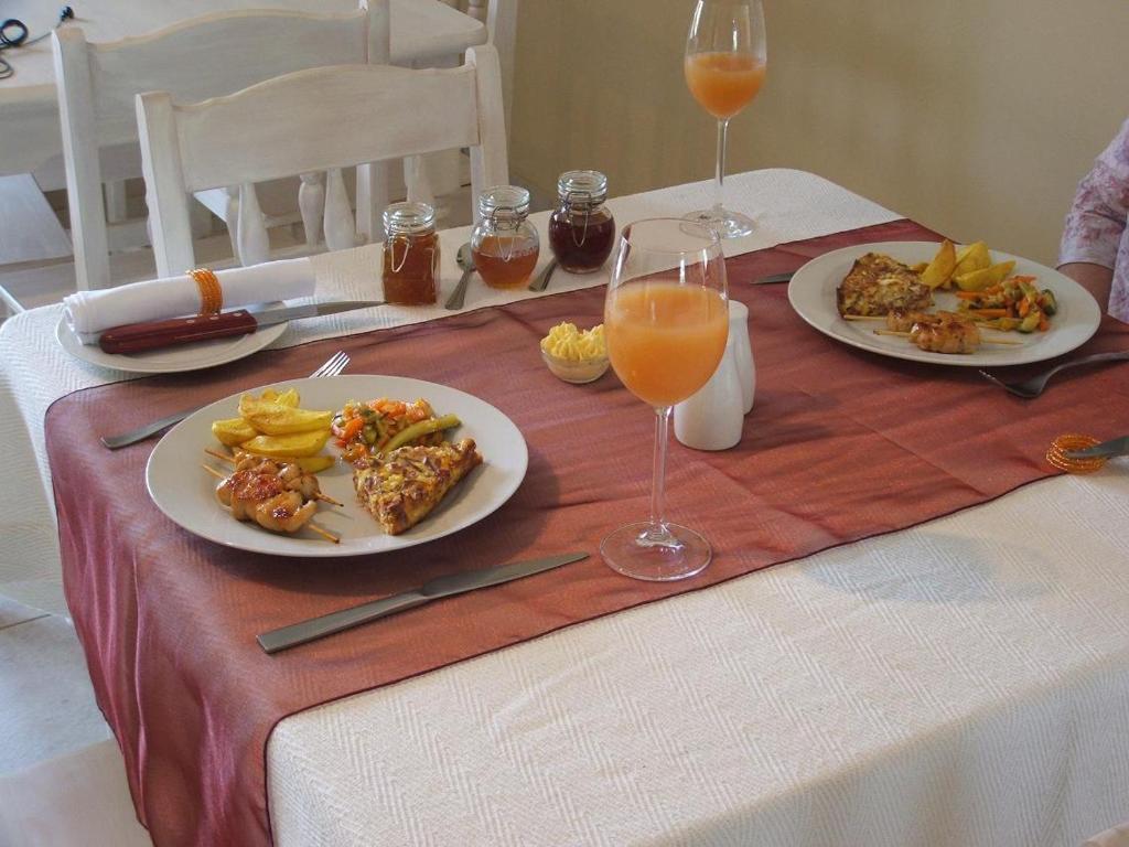 una mesa con platos de comida y vasos de zumo de naranja en Melody Guest House, en Centurion