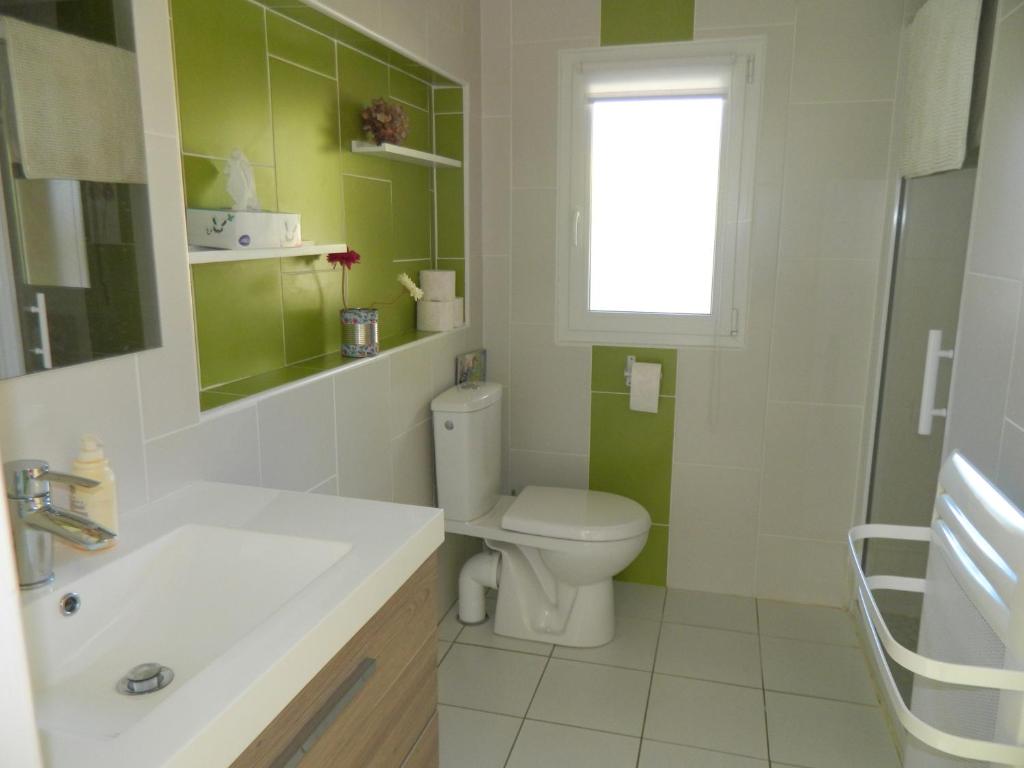 baño con aseo y lavabo y ventana en Maisonnette rénovée, en Lacrabe