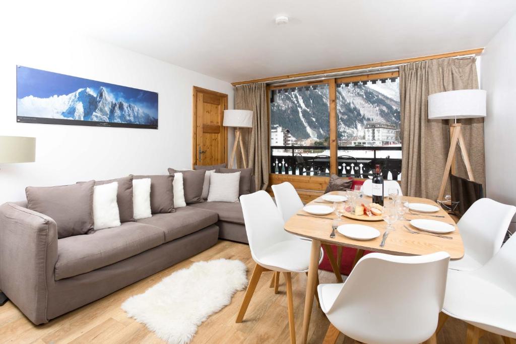 a living room with a couch and a table and chairs at Les Balcons du Savoy 104 appt - Chamonix All Year in Chamonix
