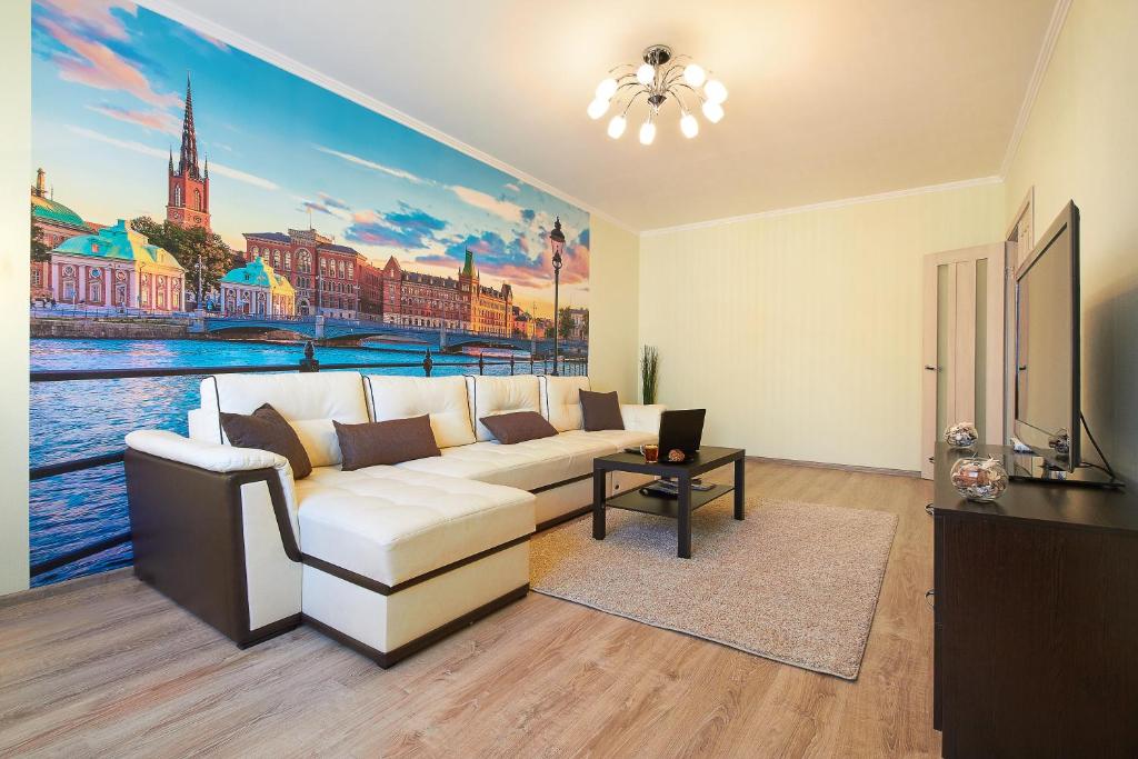 a living room with a white couch and a painting at PaulMarie Apartments on Mazurova in Gomel