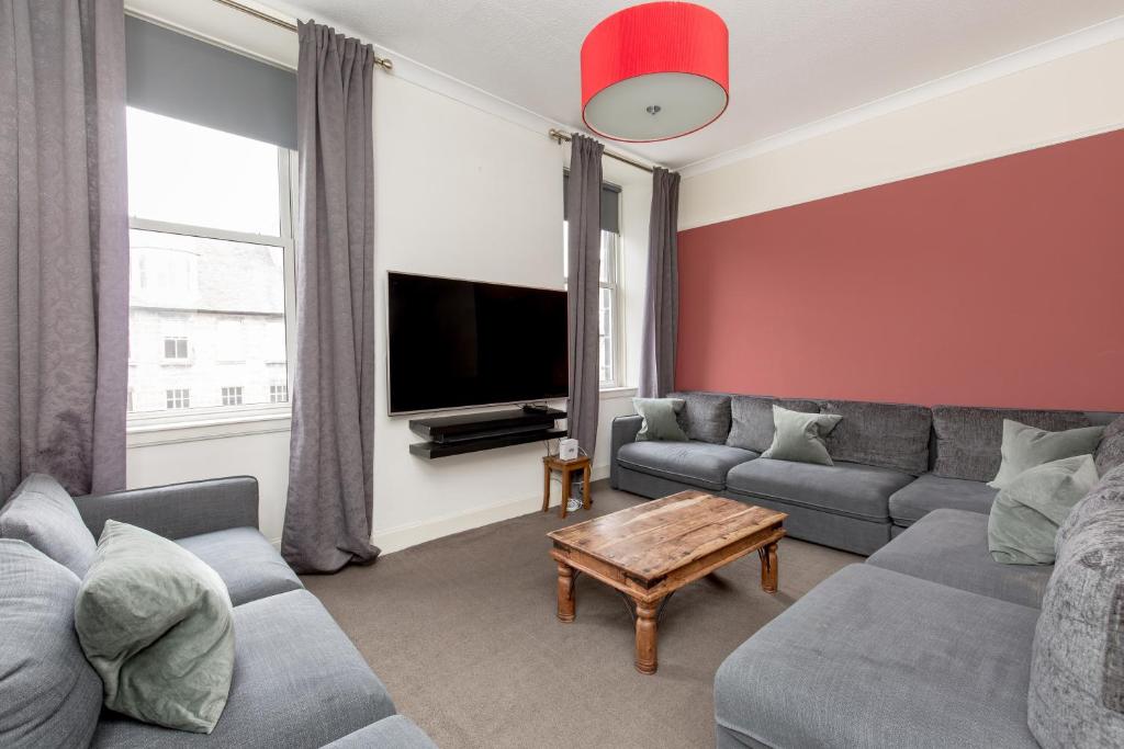 uma sala de estar com um sofá e uma televisão em Rose Street Residence em Edimburgo