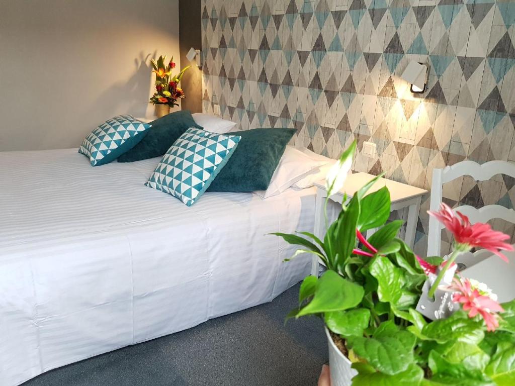 1 dormitorio con cama blanca con almohadas azules y escritorio en Hôtel Picardia en Saint-Valery-sur-Somme