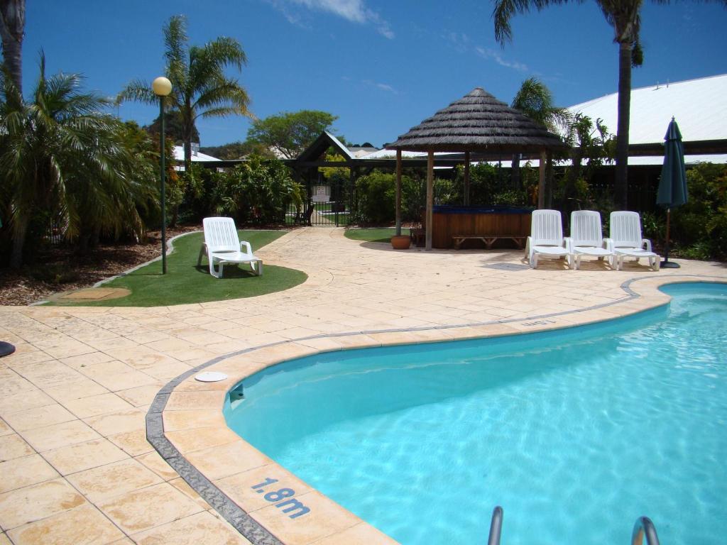a beach with a pool, chairs, and a lawn chair at Dunsborough Central Motel in Dunsborough