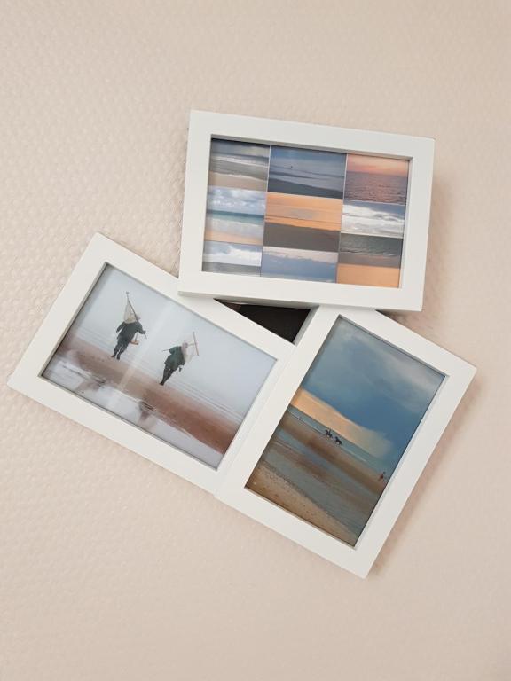 three photographs of a beach in frames on a wall at Hotel de Normandie in Saint-Aubin-sur-Mer