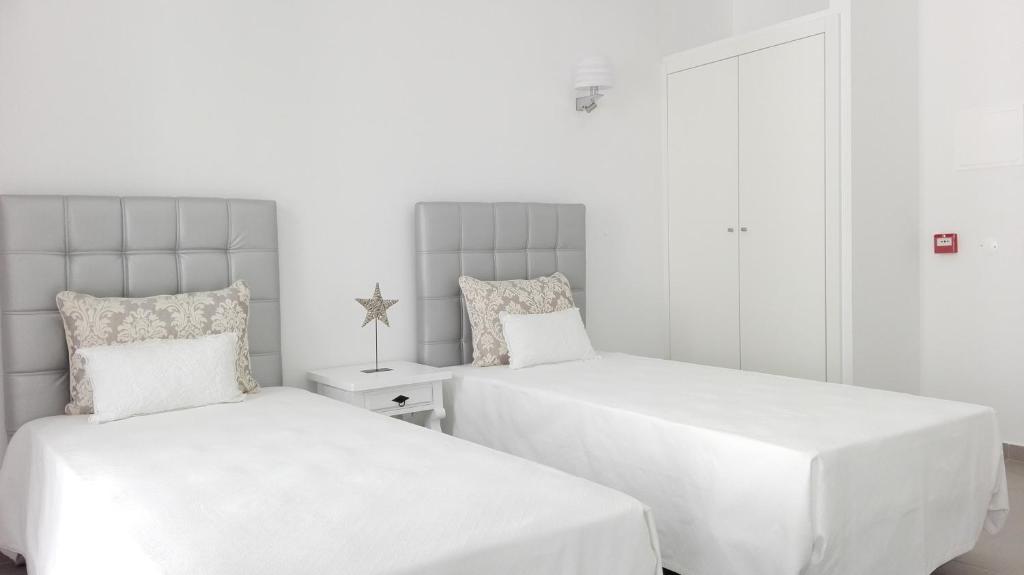 two beds in a room with white walls at Casa do Rio in Alcácer do Sal