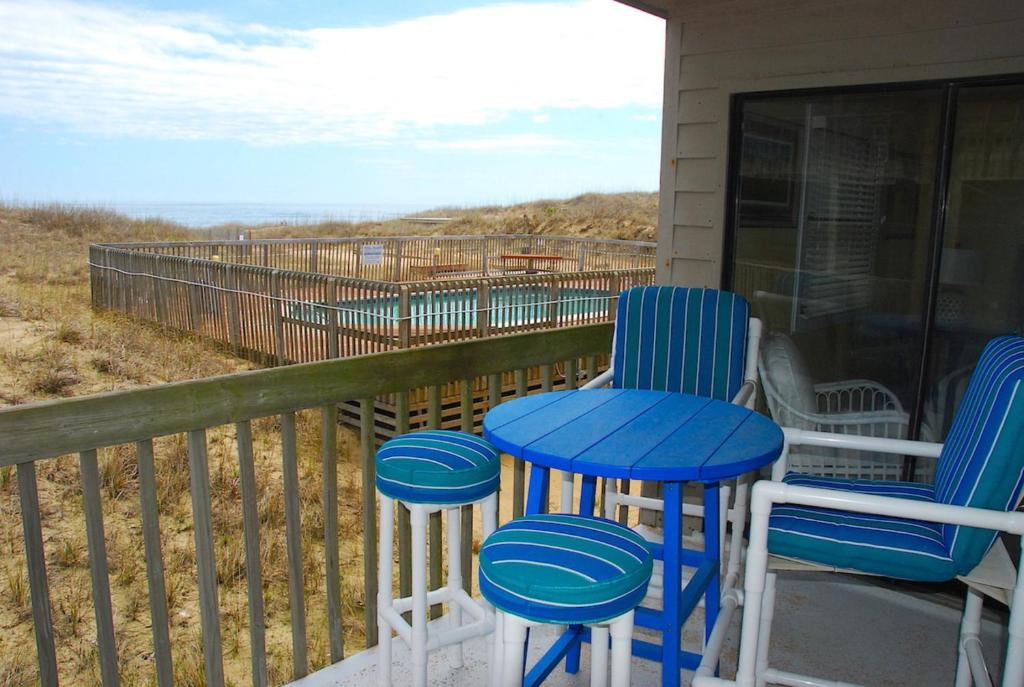 een veranda met blauwe krukken en uitzicht op de oceaan bij Admirals View III by KEES Vacations in Kill Devil Hills