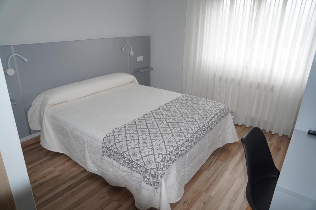 Un dormitorio con una cama con una manta. en Pension Perez, en Portomarín