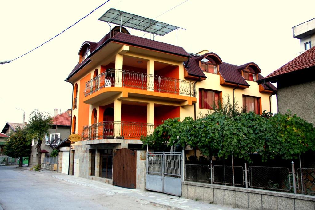 um edifício amarelo e laranja com um solarvisor em cima em Guest House Stelia em Velingrad