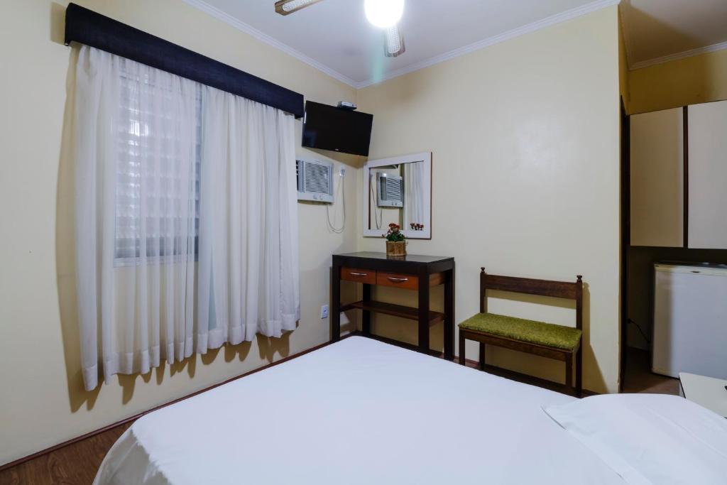 a bedroom with a bed and a chair and a window at Hotel Acacia in São Caetano do Sul