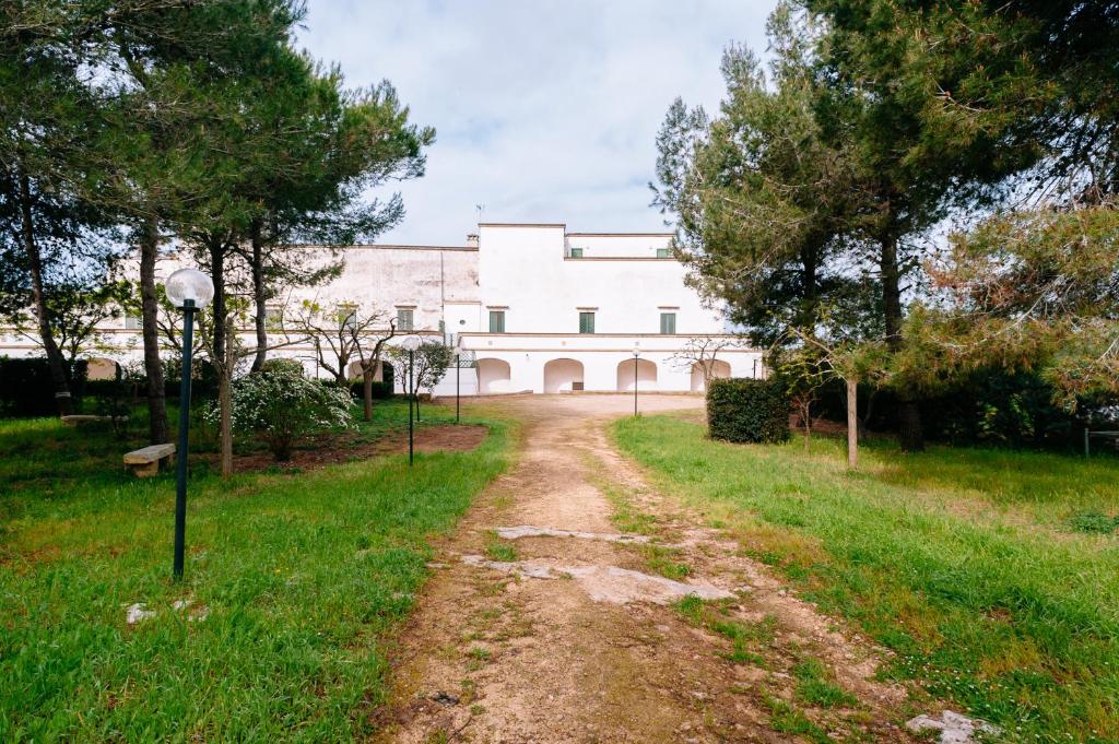 un chemin de terre devant un bâtiment blanc dans l'établissement Agriturismo Francesca Stajano, à Alezio