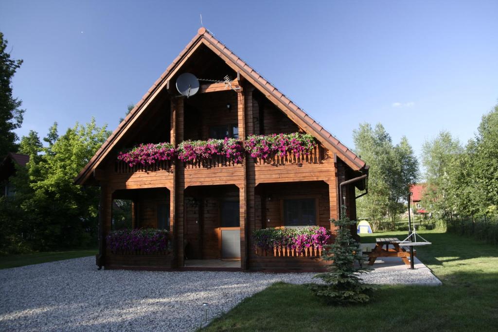 una pequeña casa de madera con flores. en Lakeside Cottage, en Sajzy