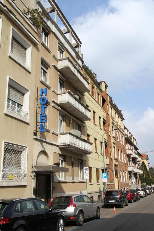 um grande edifício com carros estacionados em frente em Hotel Corallo em Milão