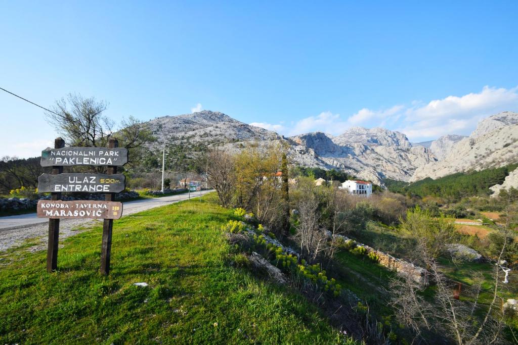 a sign on the side of a road with mountains in the background at Apartments Paklenica in Starigrad