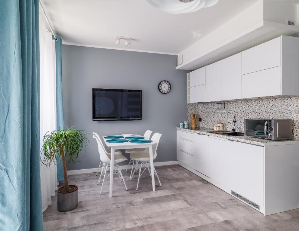 a kitchen with white cabinets and a table and chairs at Wyspa Uznam - Kwartał Róży Wiatrów in Świnoujście