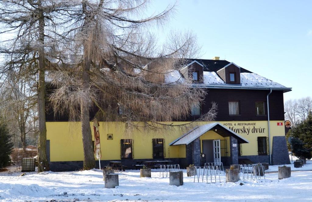 żółto-czarny budynek w śniegu w obiekcie Hotel & Restaurant Adolfovský Dvůr w mieście Adolfov