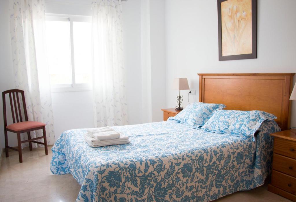 sypialnia z łóżkiem z niebieskim kocem i krzesłem w obiekcie Apartamentos Turísticos Fercomar w mieście Nerja