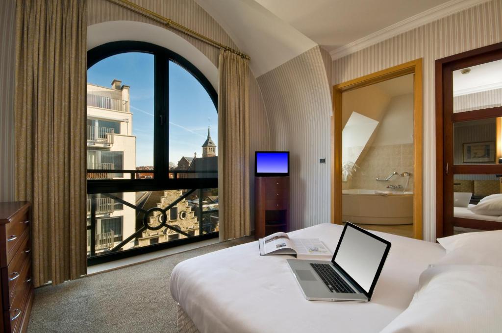 a hotel room with a bed with a laptop and a window at B-aparthotel Ambiorix in Brussels