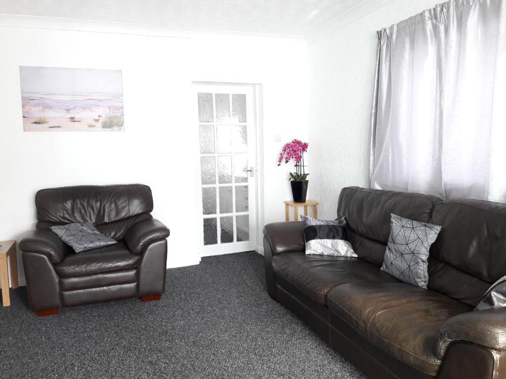 a living room with a leather couch and a chair at Springfield Holiday Apartments in Skegness