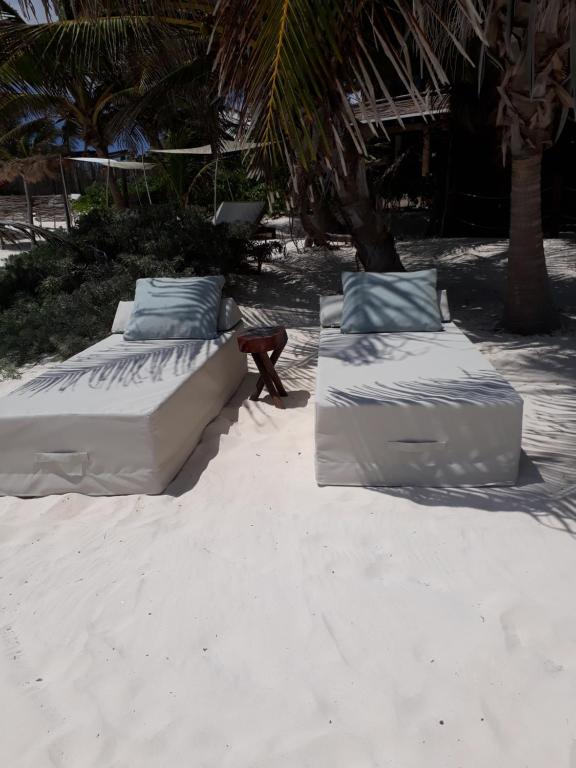 dos camas sentadas en la arena de la playa en Azucar Hotel Tulum, en Tulum