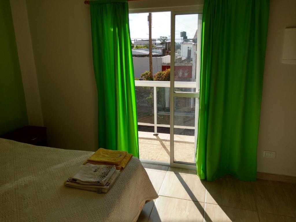 a bedroom with green curtains and a window with a view at Gala in Paso de los Libres