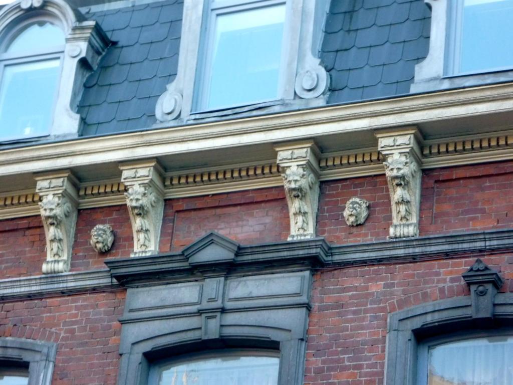 un bâtiment en briques avec des gargoyles dessus dans l'établissement Les Gîtes Du Pays De Charleroi, à Charleroi