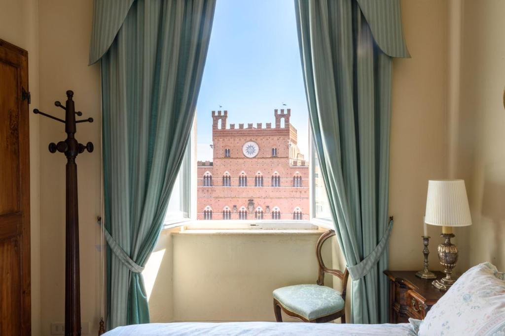 a bedroom with a bed and a window with a building at Palazzo Lenzi in Siena