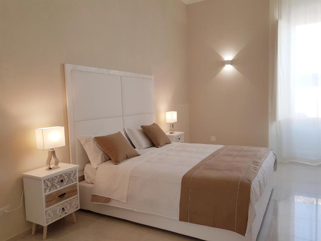 シラクーサにあるB&B Via Cavour 32の白いベッドルーム(ランプ2つ付きの大型ベッド1台付)