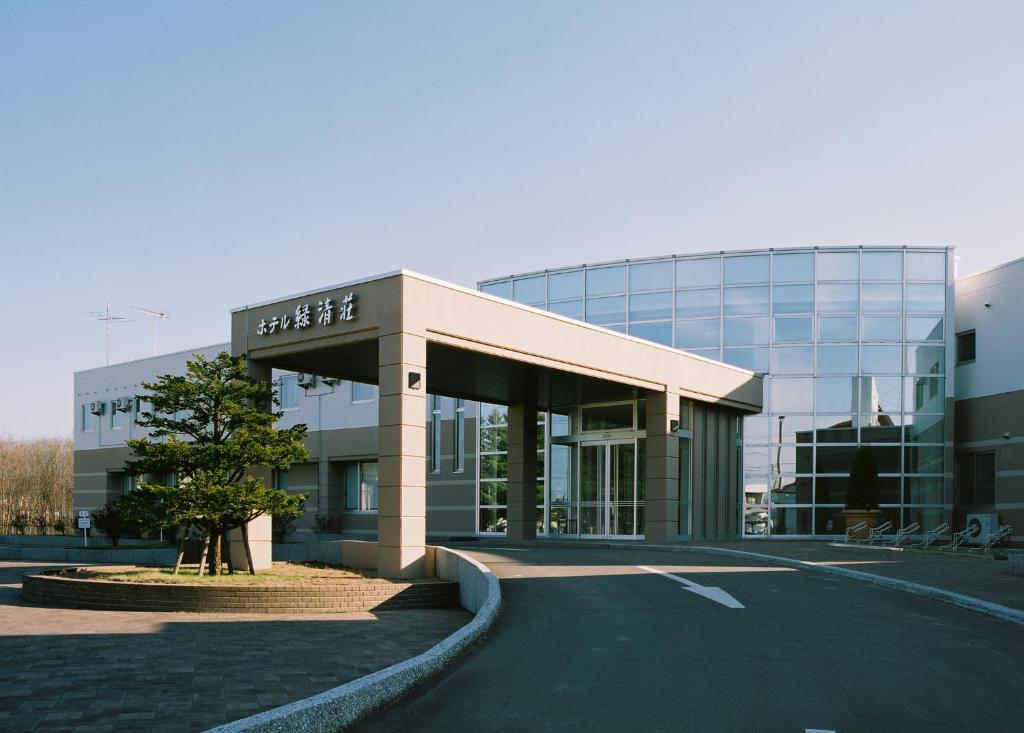un gran edificio de cristal con un árbol delante de él en Kiyosato Onsen Hotel Ryokuseisou, en Kiyosato