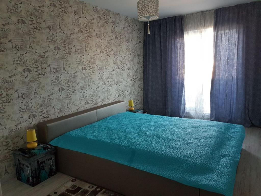 a bedroom with a bed with a blue blanket on it at Viv Apartments 65 in Floreşti