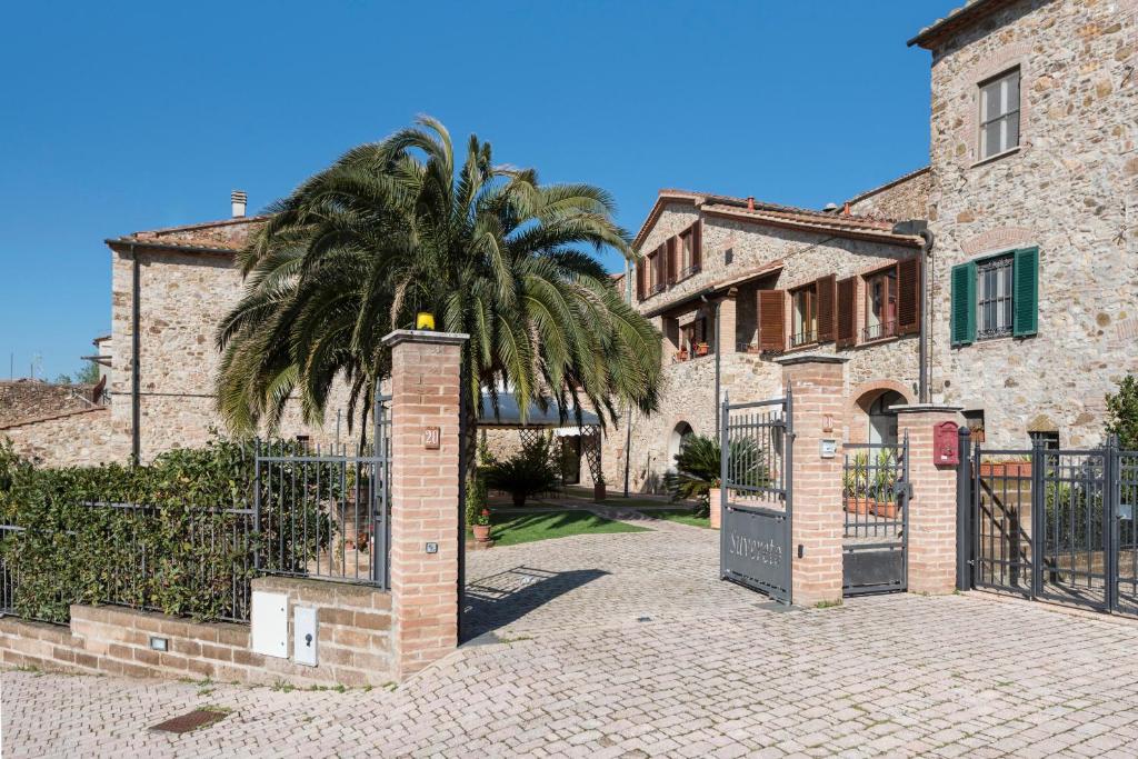 a palm tree in front of a building with a gate at Bed & Breakfast Suvereto in Suvereto