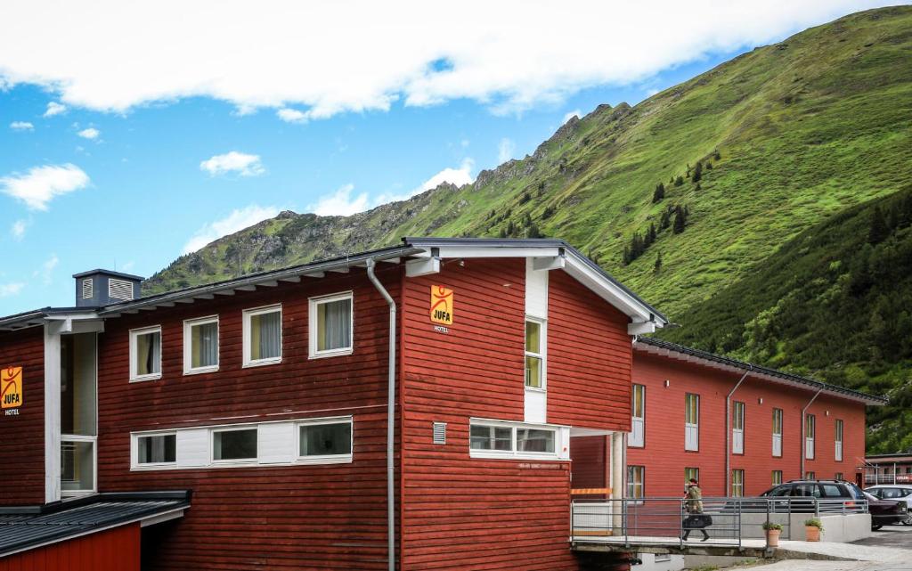 a red building with a mountain in the background at JUFA Hotel Planneralm in Planneralm