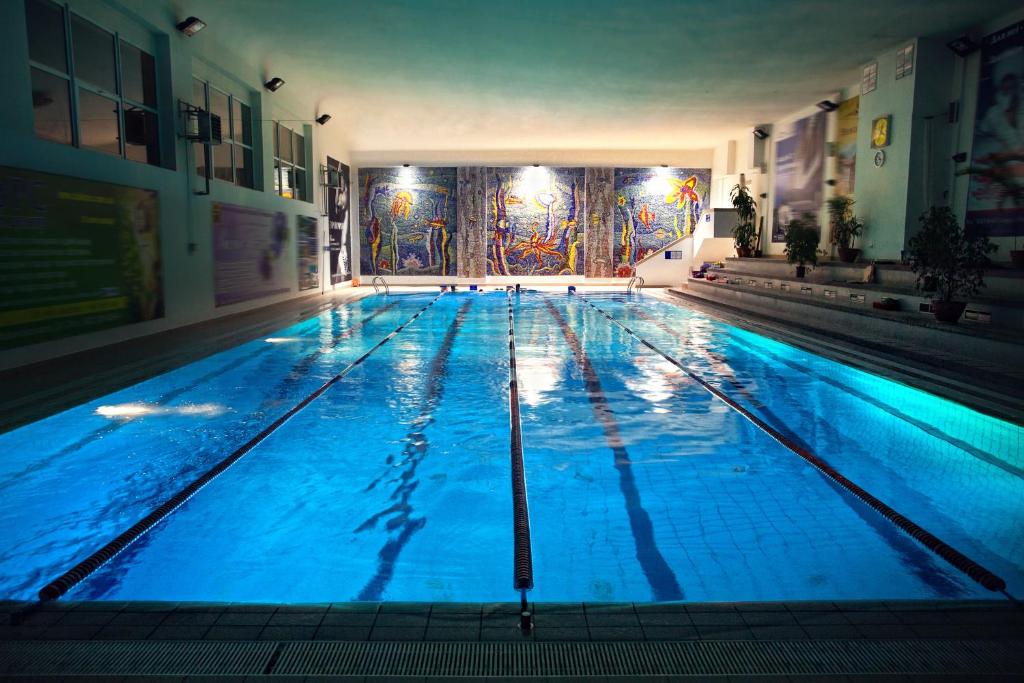 - une grande piscine avec éclairage bleu dans un bâtiment dans l'établissement LH Hotel&SPA, à Lviv