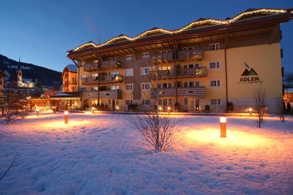 a building with lights in the snow at night at Adler ApartHotel in Moena