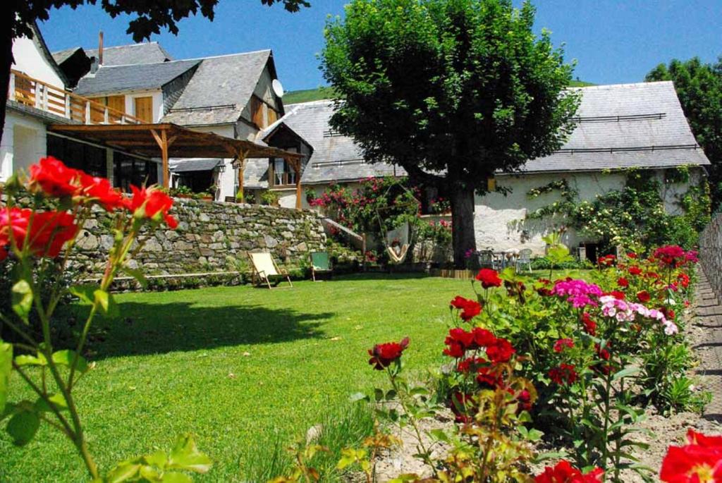 une maison avec une cour ornée de fleurs rouges dans l'établissement Gite Auberge La Soulan - gite de montagne, à Cathervielle