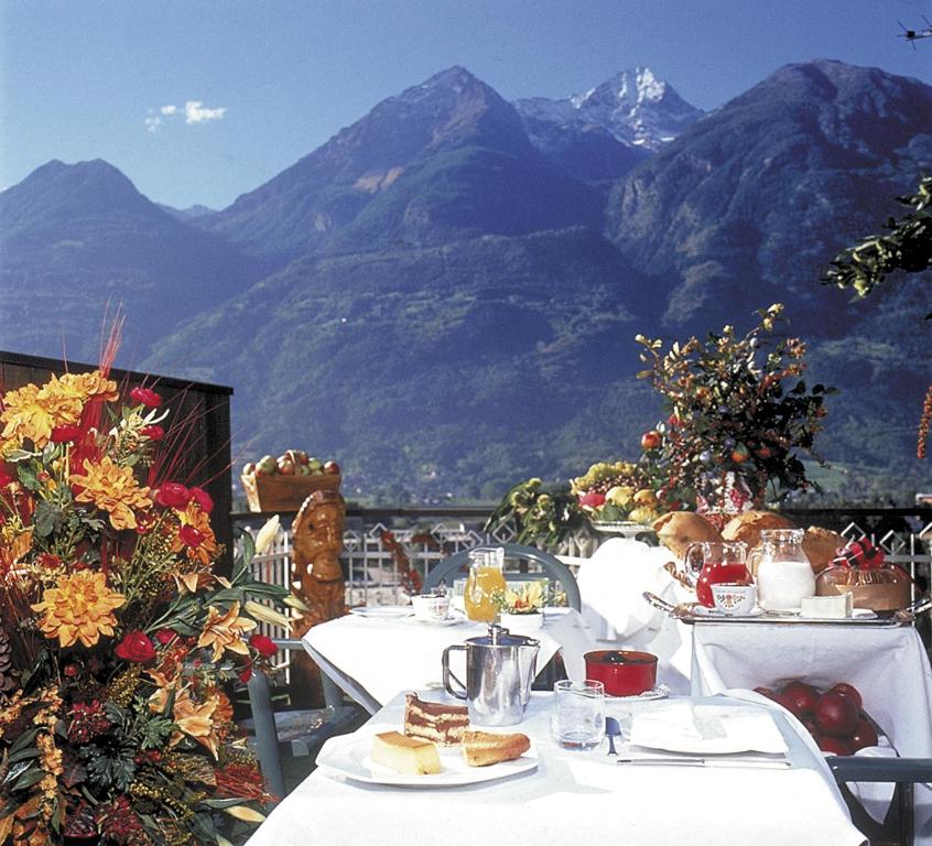 une table avec de la nourriture sur elle et des montagnes en arrière-plan dans l'établissement Hotel Casale, à Aoste