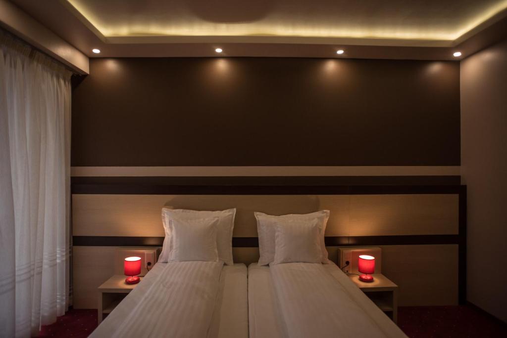 Homorod Hotel في بايلي هومورود: غرفة نوم بسرير مع شموعين حمراء
