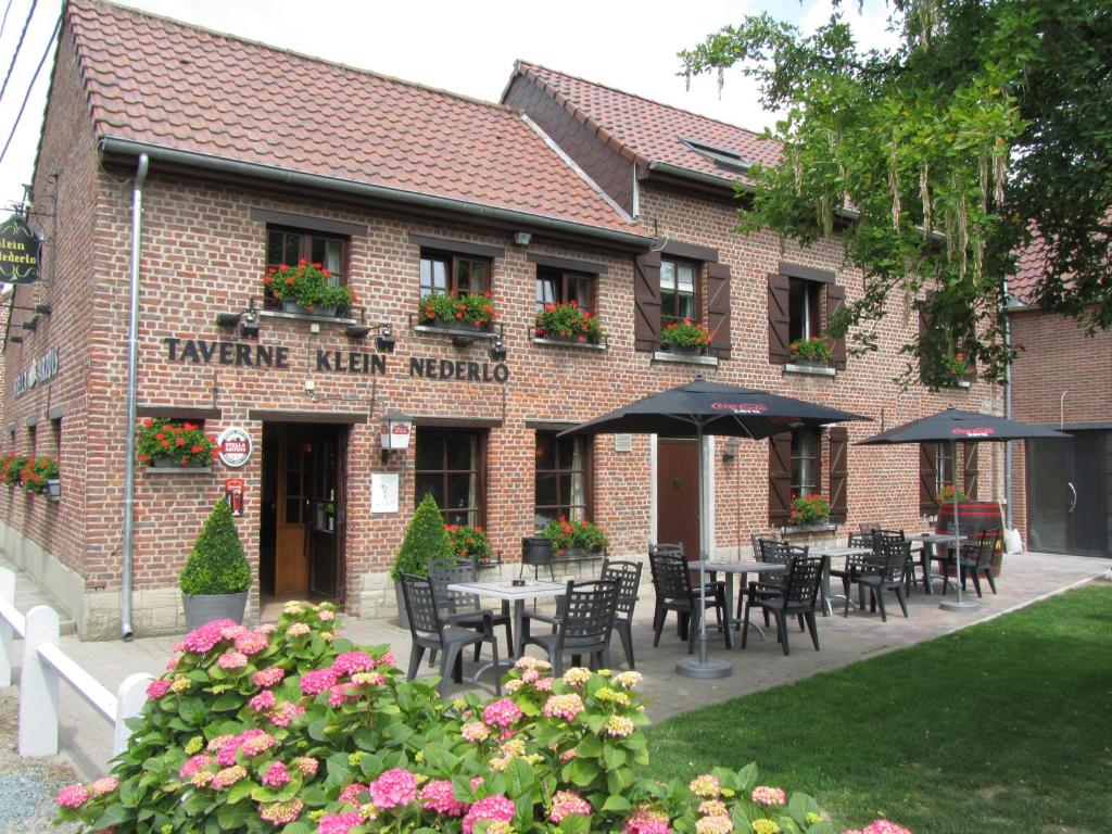 een restaurant met tafels en stoelen voor een gebouw bij Hotel Klein Nederlo in Vlezenbeek