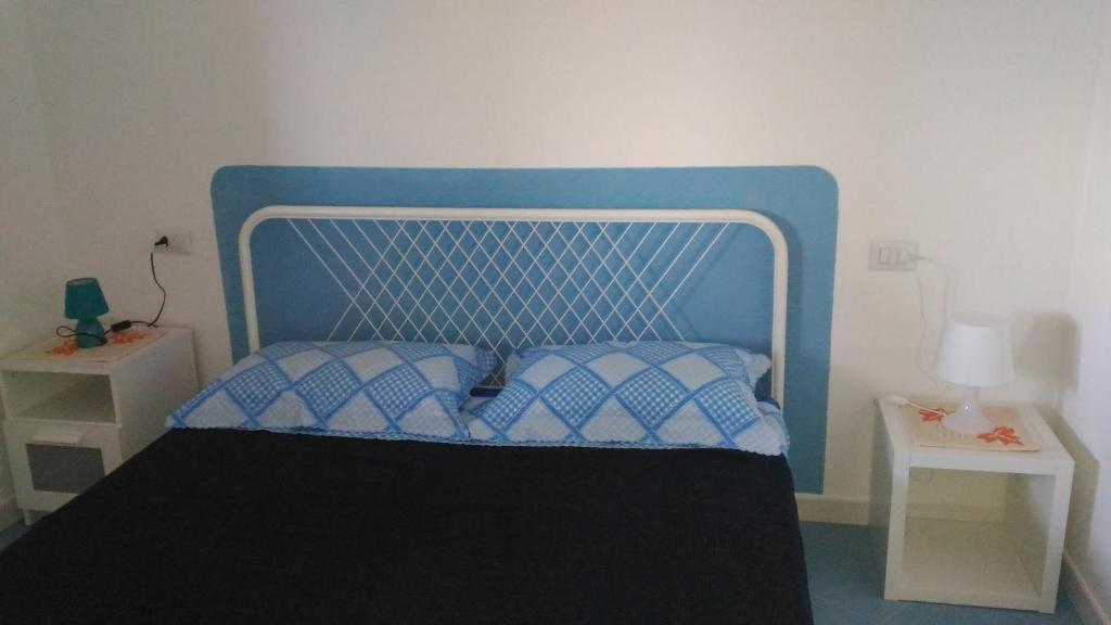 カステルサルドにあるLe Conchiglieのベッド1台(青いヘッドボード、ナイトスタンド付)