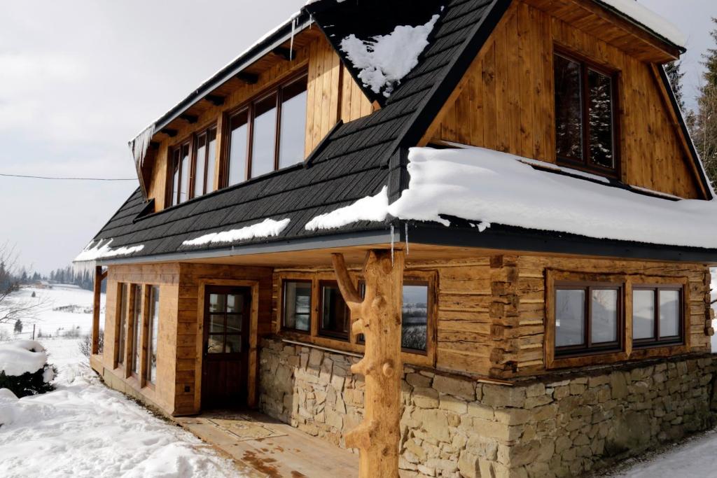 a log cabin with snow on the roof at Buflaczanka in Nowy Targ