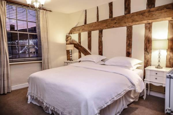 a bedroom with a large white bed and a window at The Angel Hotel in Lavenham