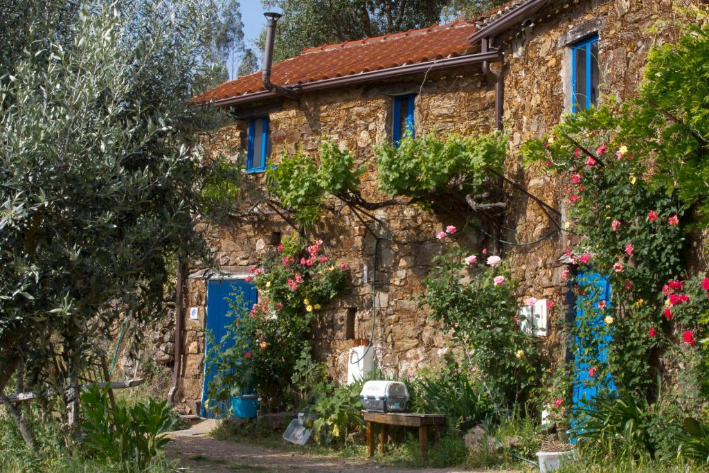 una antigua casa de piedra con puertas azules y flores en Guest Room B&B Agro-turismo Quinta da Fonte, en Figueiró dos Vinhos