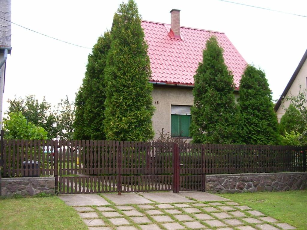 uma cerca em frente a uma casa com árvores em Arany apartman Zsóry em Mezőkövesd