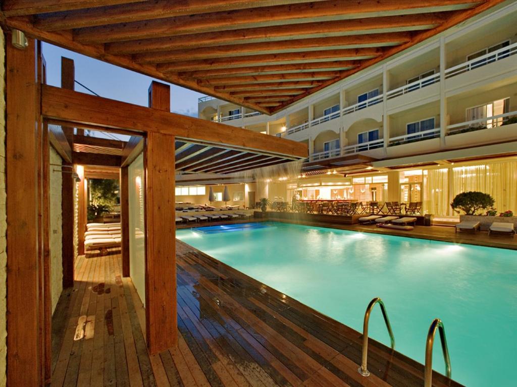 a large swimming pool in a hotel with a wooden deck at Athineon Hotel in Rhodes Town