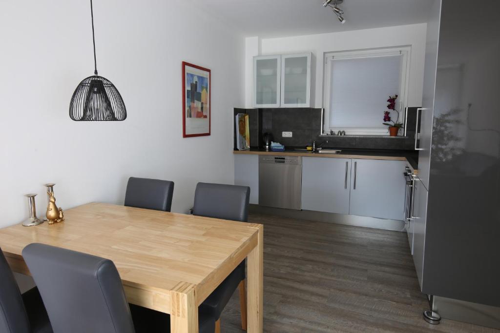 cocina y comedor con mesa de madera y sillas en City Apartment - Lüneburg Am Schierbrunnen, en Lüneburg