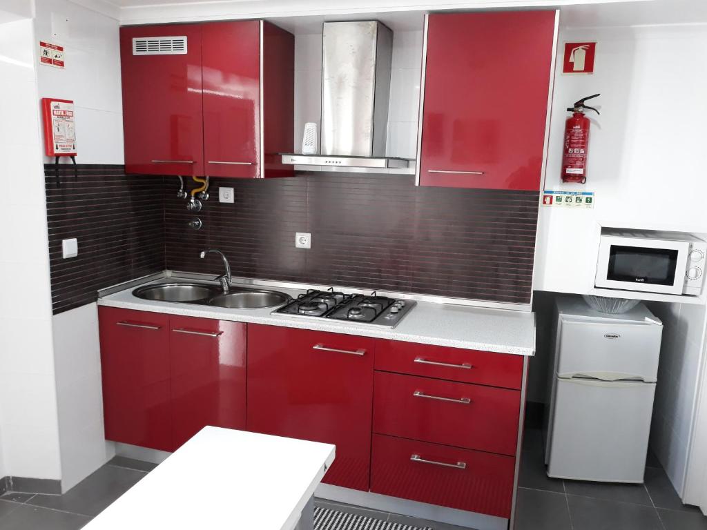 een keuken met rode kasten en een wastafel bij Nazaré - The Little Star in Nazaré