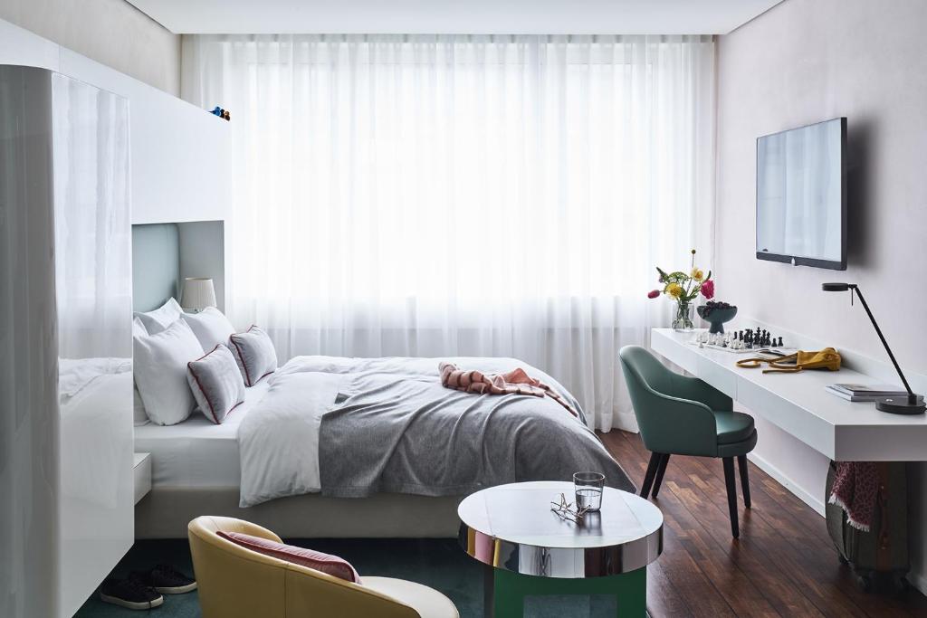 a bedroom with a bed and a desk and a bed and a window at SIDE, Hamburg, a Member of Design Hotels in Hamburg