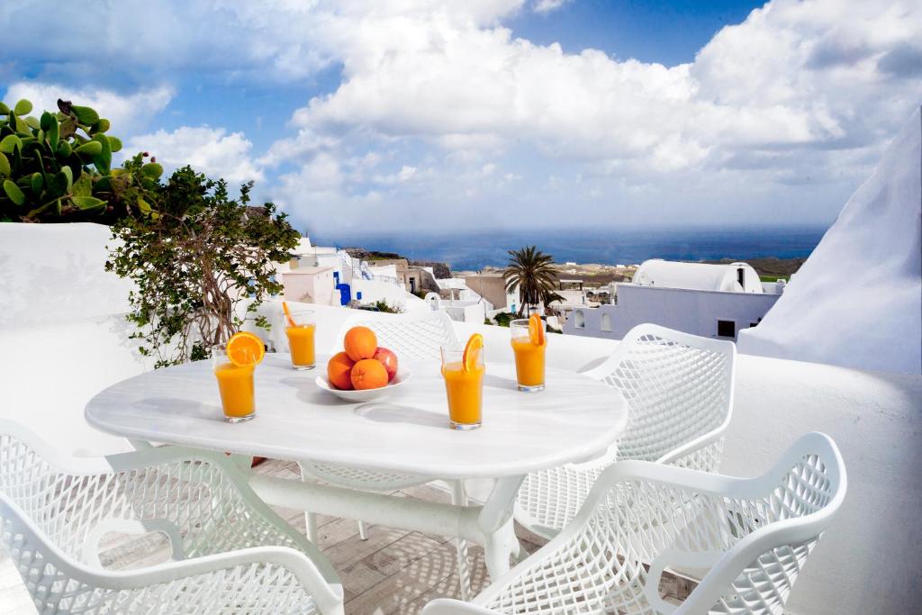 una mesa blanca y sillas en un balcón con zumo de naranja en Spilies by Thireas, en Vourvoúlos