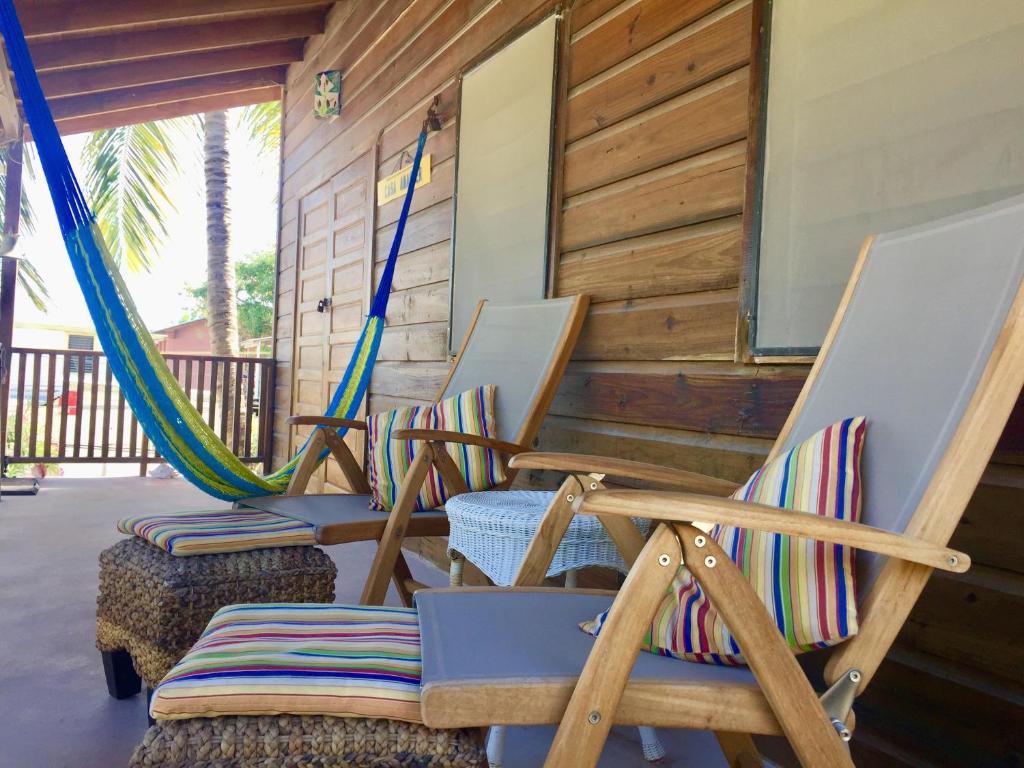 three rocking chairs and hammocks on a porch at Amanda's Place Casa Amancer - sea view, pool and tropical garden in Caye Caulker