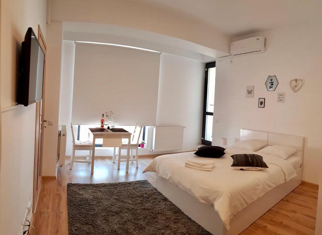 a white bedroom with a bed and a table at Studio Confort 3 in Bucharest